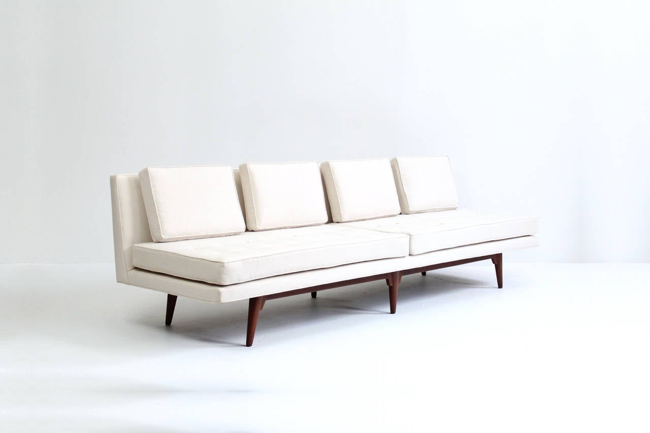 Elegant and modern armless sofa by Edward Wormley for Dunbar. This sofa is part of a sectional seating group and can stand alone or be combined with the other piece offered here. Elegantly reupholstered in linen with leather button detailing.