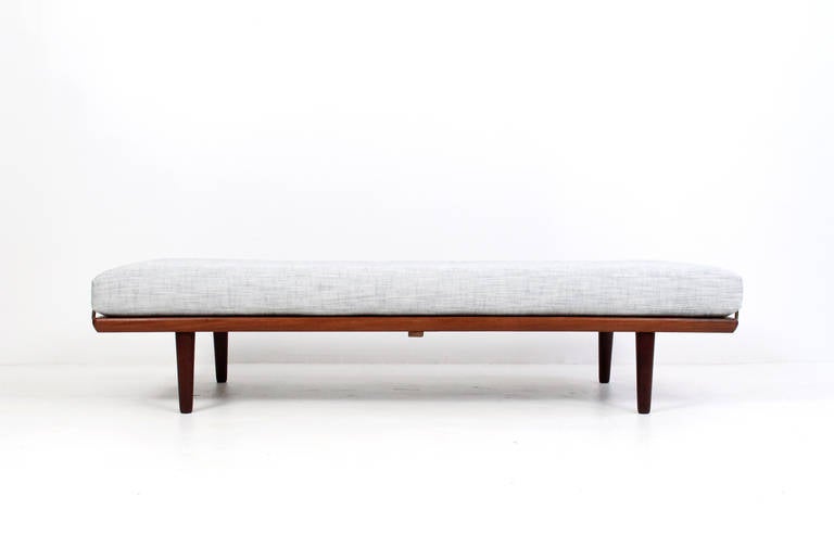 Tastefully designed tufted daybed by Hans Wegner for Getama.  Solid teak and pine frame with brass supports that hold the cushion in place.  Original Georg Jensen paper label to underside. Recently reupholstered.