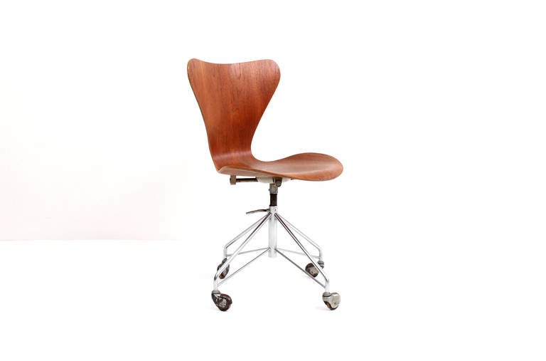 Arne Jacobsen for Fritz Hansen teak desk or task office chair with sculptural teak seat and a chrome plated steel base with rolling casters.  Signed with Fritz Hansen foil label to base and impressed marks to other components. Chair adjusts between