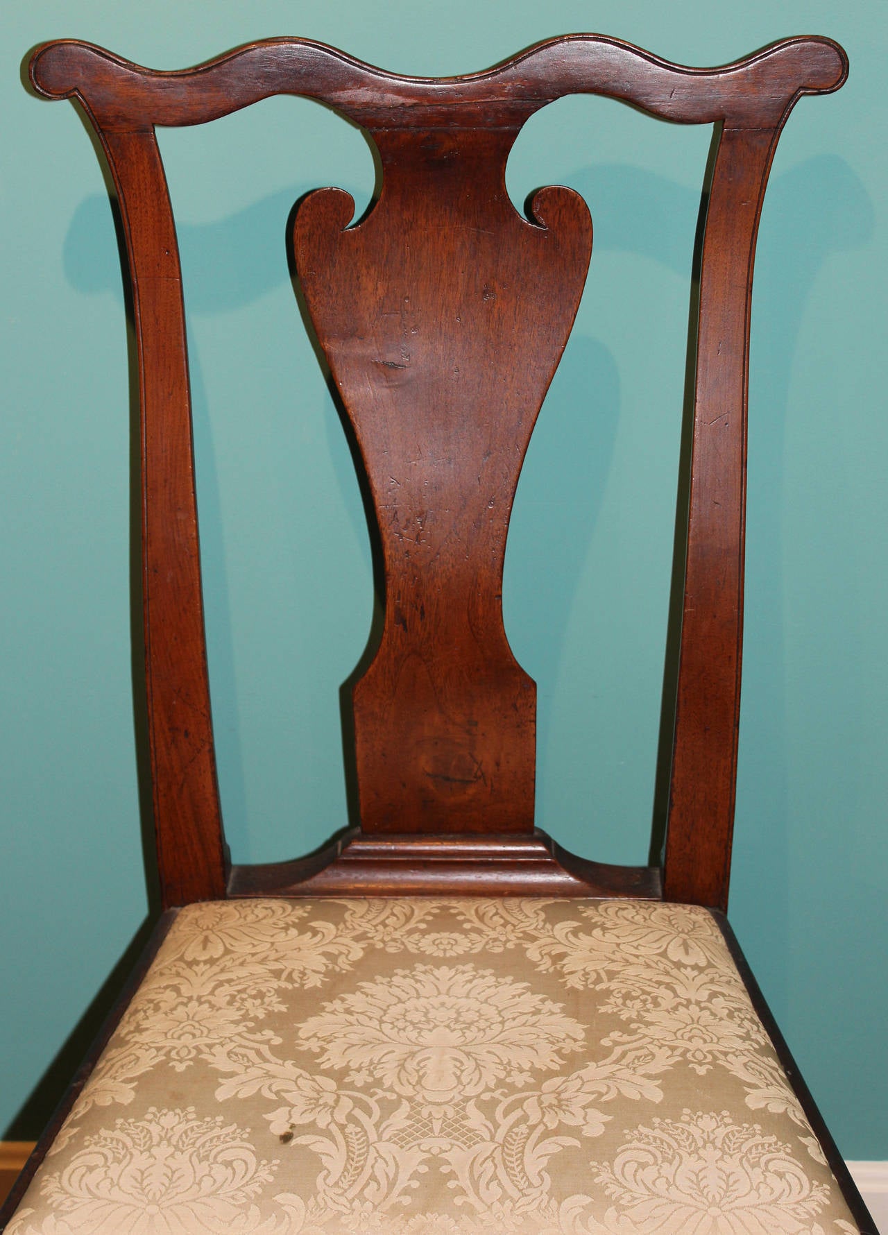 A fine example of a Philadelphia Queen Anne Walnut Side Chair, circa 1755, probably the workshop of William Savery. Incised cupid's bow crest above a solid vasiform splat and trapezoidal slip seat supported by cabriole legs terminating in trifid