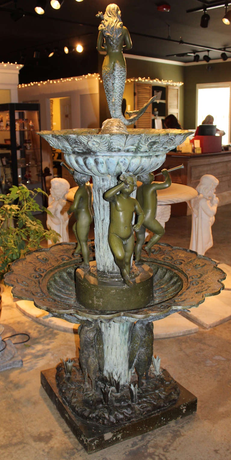 This wonderful 20th century tiered fountain, after Auguste Moreau,  is made of bronze, with a mermaid at the top, three putti with musical instruments supporting the top scalloped tier, three geese supporting the bottom larger scalloped tier, all