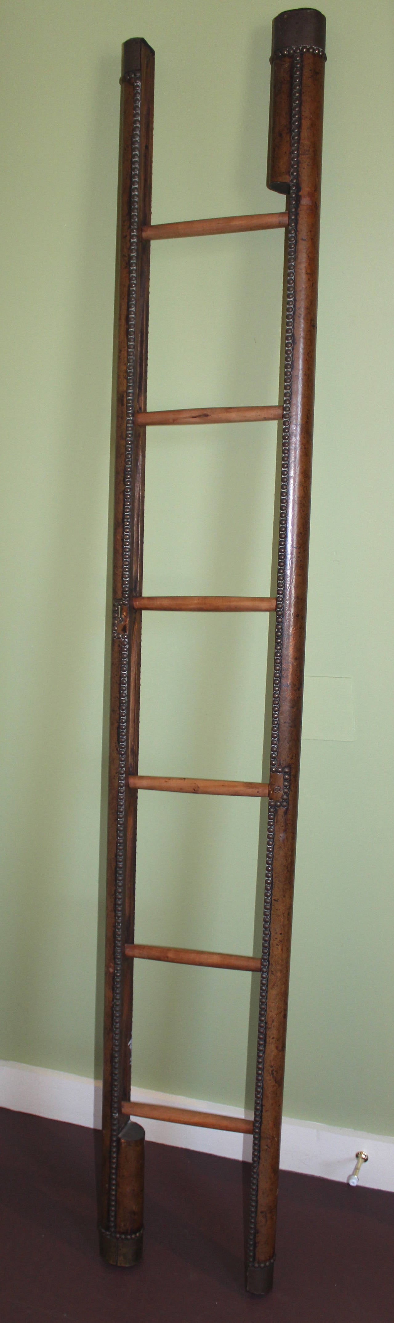 Regency Style Leather-Bound Folding Library Ladder, probably late 19th or early 20th C. English, bound in dark brown leather with brass ends and brass tack trim and latch, the wooden ladder folding into a single unit.