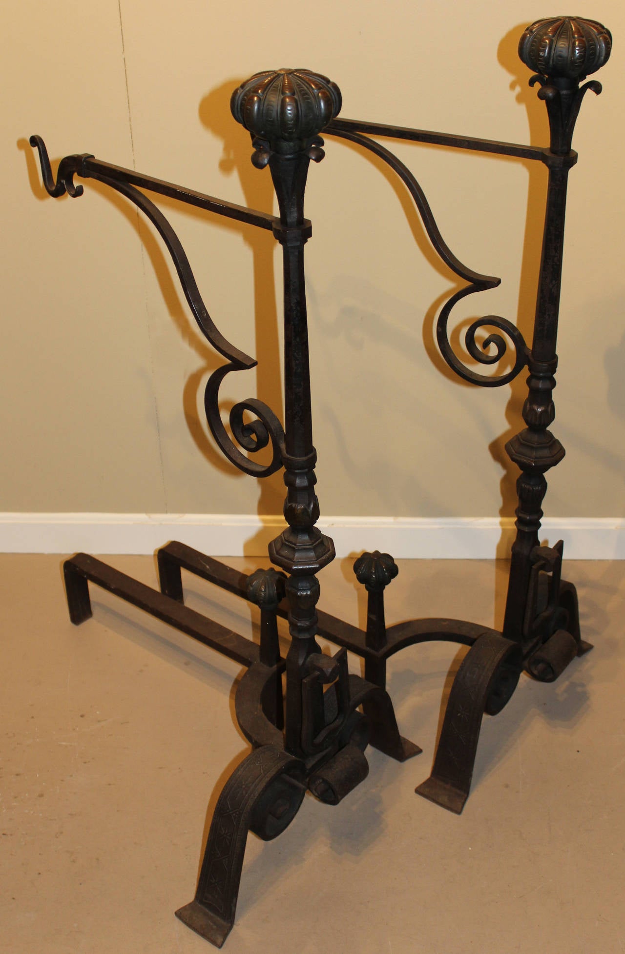 A fine and unique pair of century old bronze and iron andirons, probably Continental. The ball tops with stylized talons, nicely scrolled swing arms with hooks. Turned posts raised by scrolled iron shoulders the log stops with corresponding ball