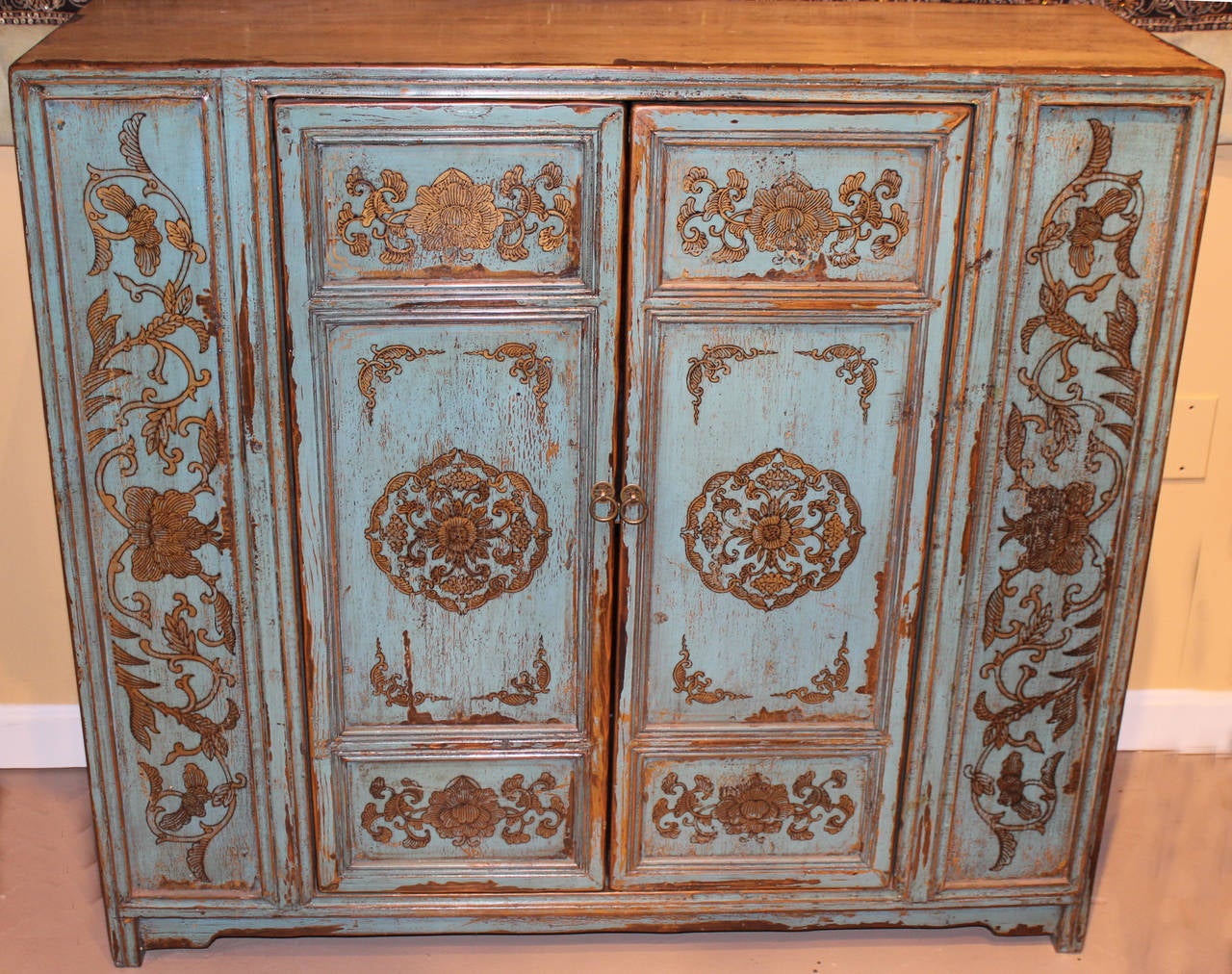 A paint decorated Chinese wooden two door cabinet, opening to a single interior shelf. The front panels are painted pale blue with gold and black foliate decoration, with ivory colored sides and top. A great piece and wonderful size. Probably dating