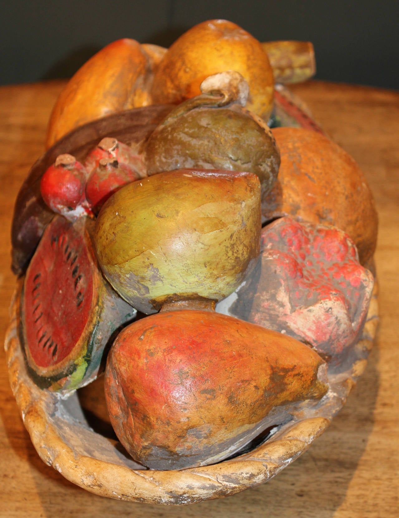 A folk art plaster centerpiece bowl of painted fruit, probably made in Mexico circa 1940, showing a variety of fruit including watermelon, pears, lemons, cherries, and other fruits. Great patina and overall condition.