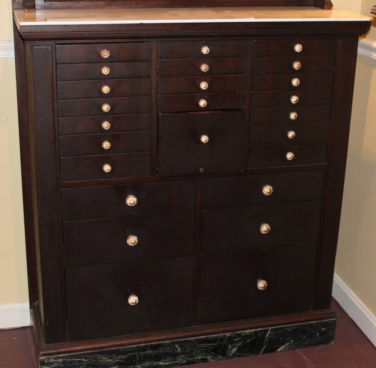 A fine example of a multi- drawer mahogany dental cabinet made by American Cabinet Company, Two Rivers Wisconsin,  circa 1920’s, with milk glass top, etched glass windows on the upper doors, opening to tin lined compartments with milk glass shelves,