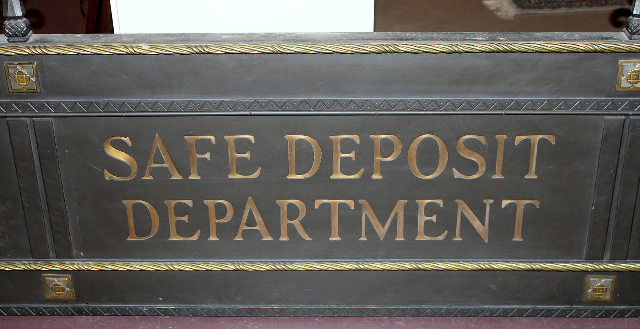 A great architectural mixed metal and bronze frieze or sign from a bank, dating to the late 19th or early 20th century, with cut out letters which read “Safe Deposit Department,” backed by a gold sheet of bronze from behind. The sign is decorated