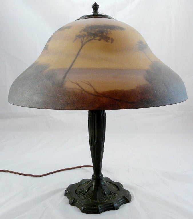 Reverse painted art glass lamp with landscape scene, circa 1920.  Possibly Pittsburgh Lamp Company.  Base probably of spelter but has a nice bronze-like patina.  Shade measures 8