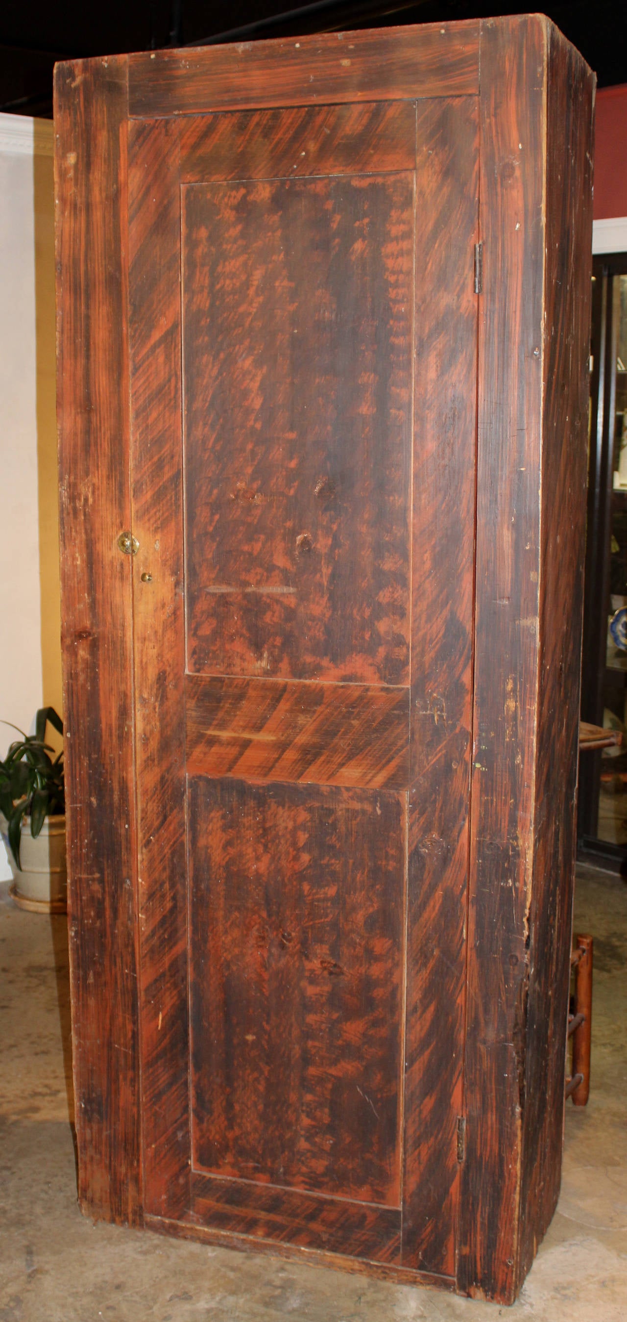 A rare pine red and black grain painted pantry cupboard, of New England origin, circa 1840, with paneled door which opens to a dry sink interior, two shelves and supports for two more, as well as a lower open compartment below the dry sink. A great