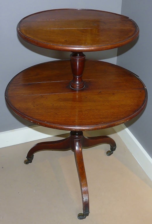 George III mahogany 2-tier stand or dumbwaiter with dish top and spider legs on castors, circa 1800.  Each tier drops and rotates.  Overall dimensions are 37