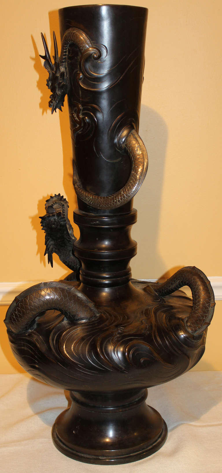 This spectacular form bronze vase features detailed dragon decoration wrapped around the body of the vase, showing the dragon slipping above and below the surface. Great patina and surface color.