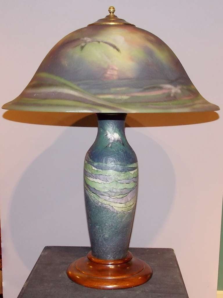A fine Pairpoint reverse-painted glass seagull lamp.  Featuring a domed flaring shade decorated with seagulls, waves and ships, raised on an illuminated baluster form vase with conforming decoration.  Chipped, ice surface, Copley form shade with