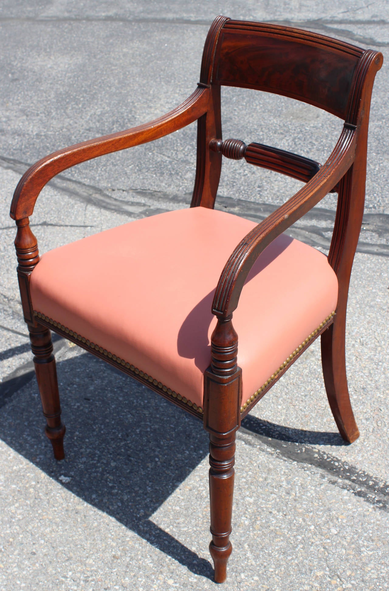 Set of 12 Regency period mahogany dining chairs, including two arm chairs and 10 side chairs. Each with a curved tablet top rail with a nicely figured mahogany panel and nicely shaped and reeded stiles centering a boldly turned and fluted center
