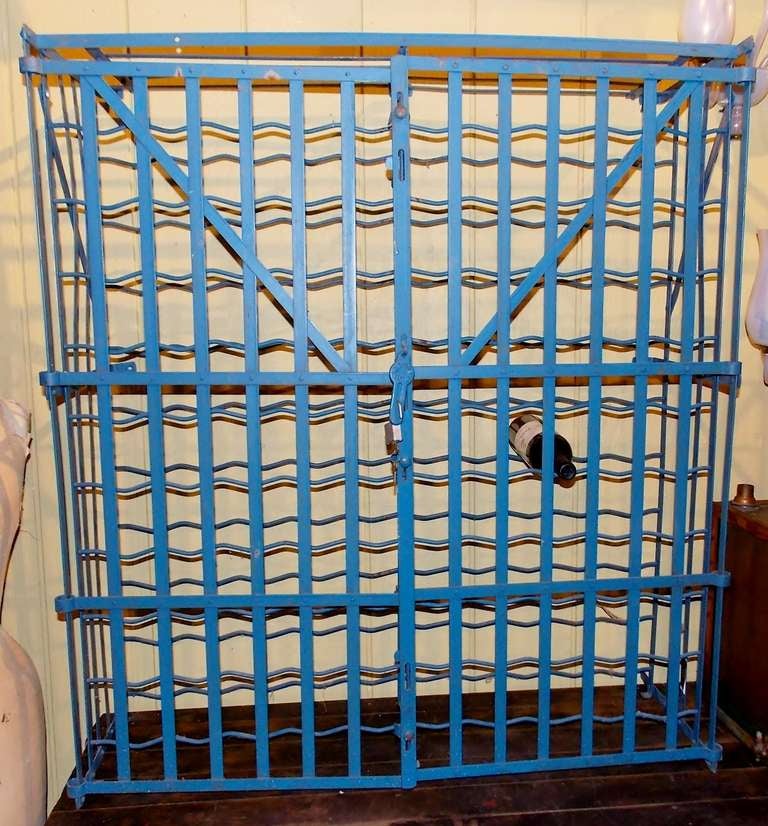 Fabulous French strap metal wine and liquor rack, circa 1930.  Blue enameled metal with 2 doors and locking hasp closure.  Can hold up to 100 bottles of wine or liquor.  Can be wall mounted in the rear.