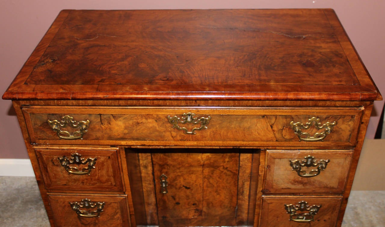 A George I period walnut kneehole desk, circa 1720.  A popular form at this time, the top drawer has a pull-out secretaire drawer that is hinged at the bottom. Unlatched this drawer front provides a leather covered writing surface. Inside the