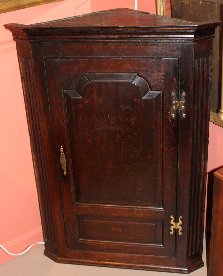 19th c English oak hanging corner cabinet, fielded paneled door, with green painted interior showing two carved interior shelves over a shelf with two small drawers, nice brasses.