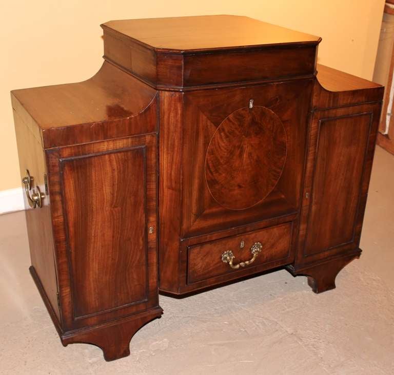 Unusual Georgian mahogany cellarette with center lift-top which opens to reveal a 9-place metal compartment.  2 side doors and one drawer.  Beautiful choice mahogany. Includes 3 keys which operate all locks.