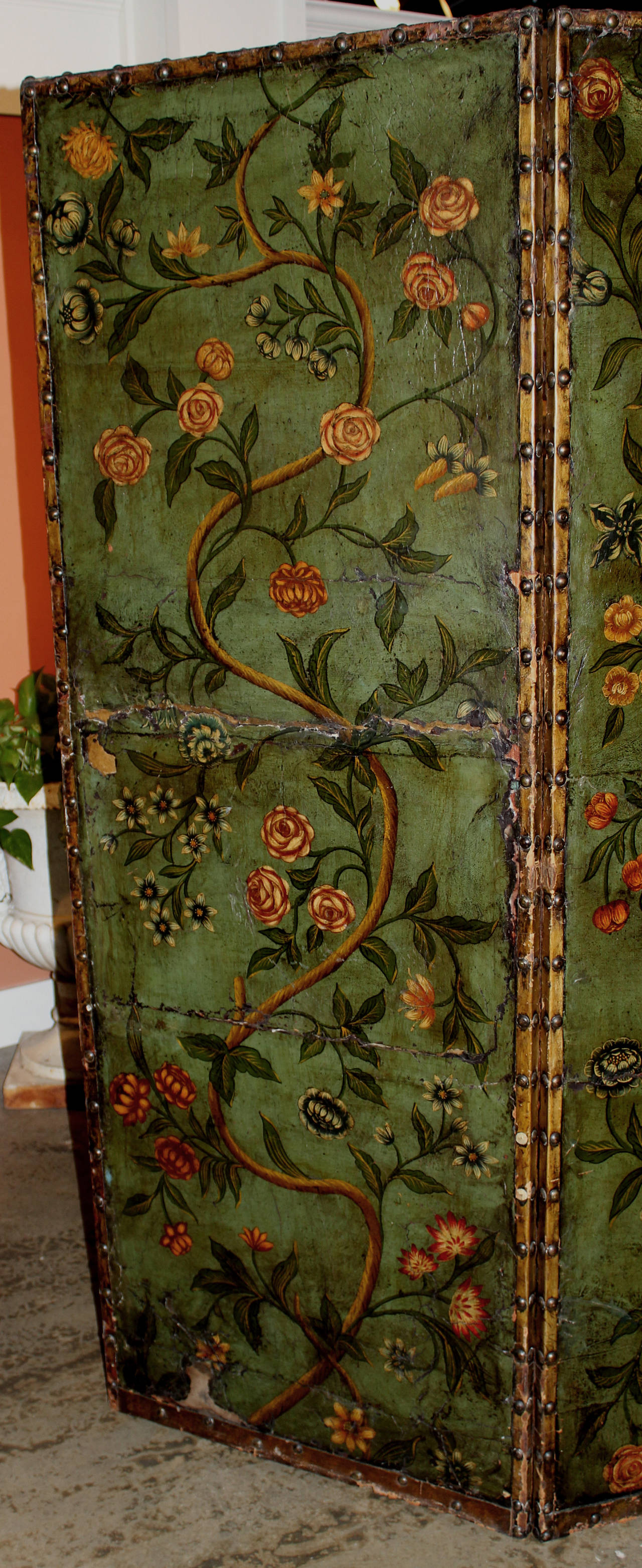 Continental dressing screen featuring polychromed 19th century leather panels decorated with a parrot, flowering trees and vines all mounted on an ebonized, hinged and paneled frame.