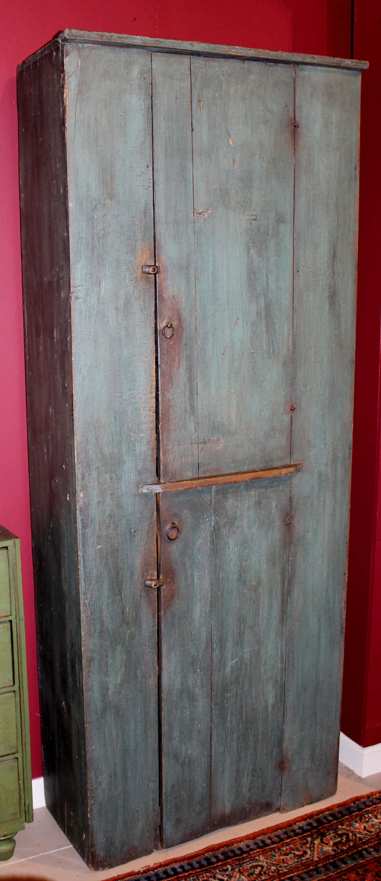 A nice example of an early 19th century two door pine cupboard in blue paint. The top door opens to two interior shelves, with the bottom door opening to one lower shelf. Each door has brass and iron ring handles.
