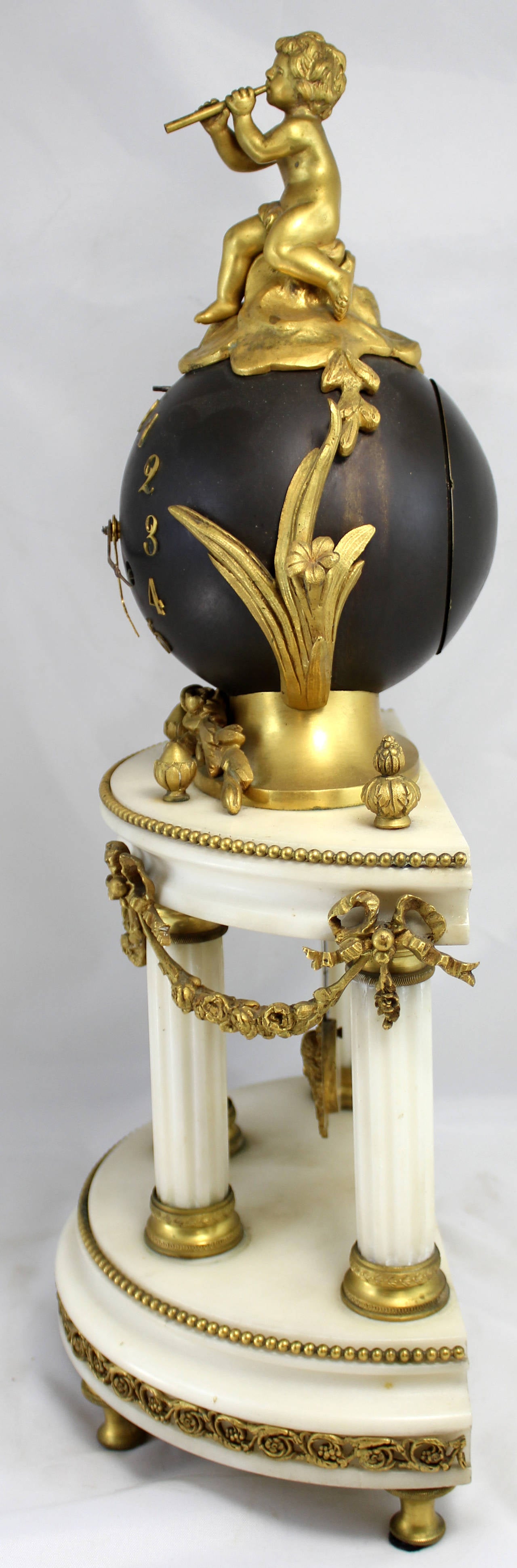 A 19th century French bronze ormolu figural clock on a demilune columned base, gilt ormolu mounts, snake form clock hands, and a putti figure sitting with flute  on the top of the globe. The brass movement is signed S H Paris. In good working