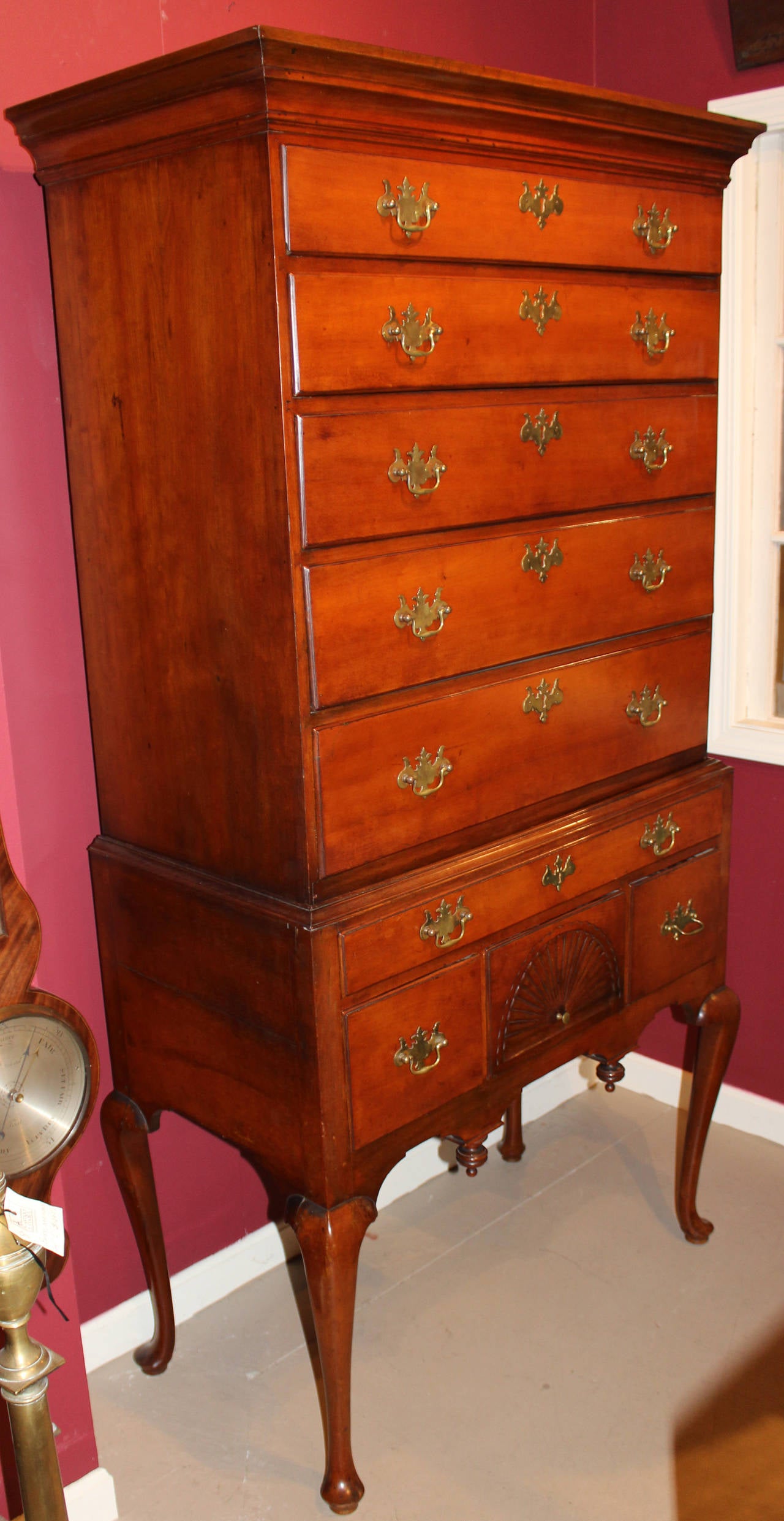 A fine 18th century cherry two part highboy, probably Connecticut in origin, with five drawer top with molded cornice over a base with one long drawer over three fitted drawers, a carved radiating fan decoration on the center drawer front, all