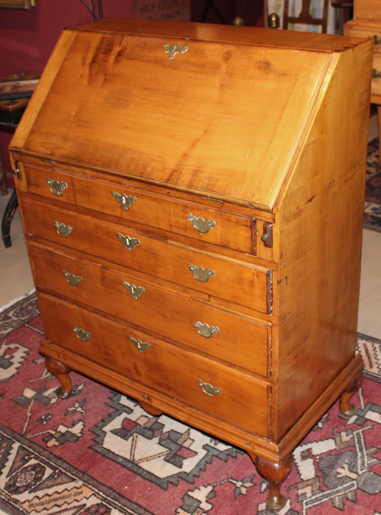 An 18th century maple Queen Anne slant front desk on frame, probably New England origin,  with nicely compartmentalized amphitheatre interior, center prospect flanked by pilaster drawers, period but not original engraved batwing hardware, with the