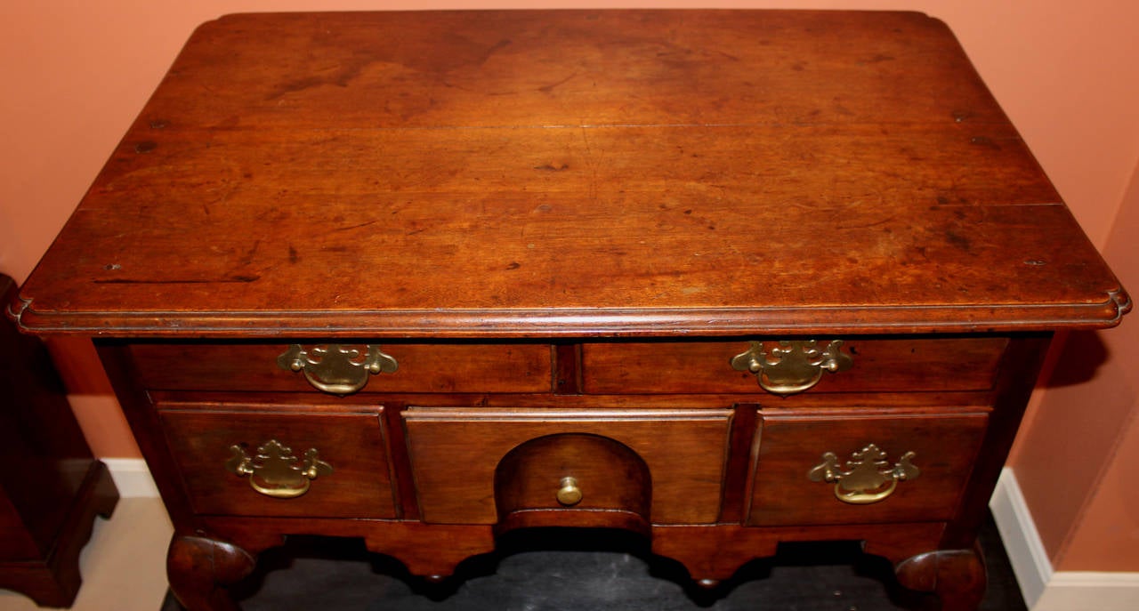 A fine example of an 18th century Massachusetts lowboy. The rectangular molded top with pinched corners above a case with one long and three aligned short drawers, the center with a molded arch above a shaped skirt and all raised by cabriole legs