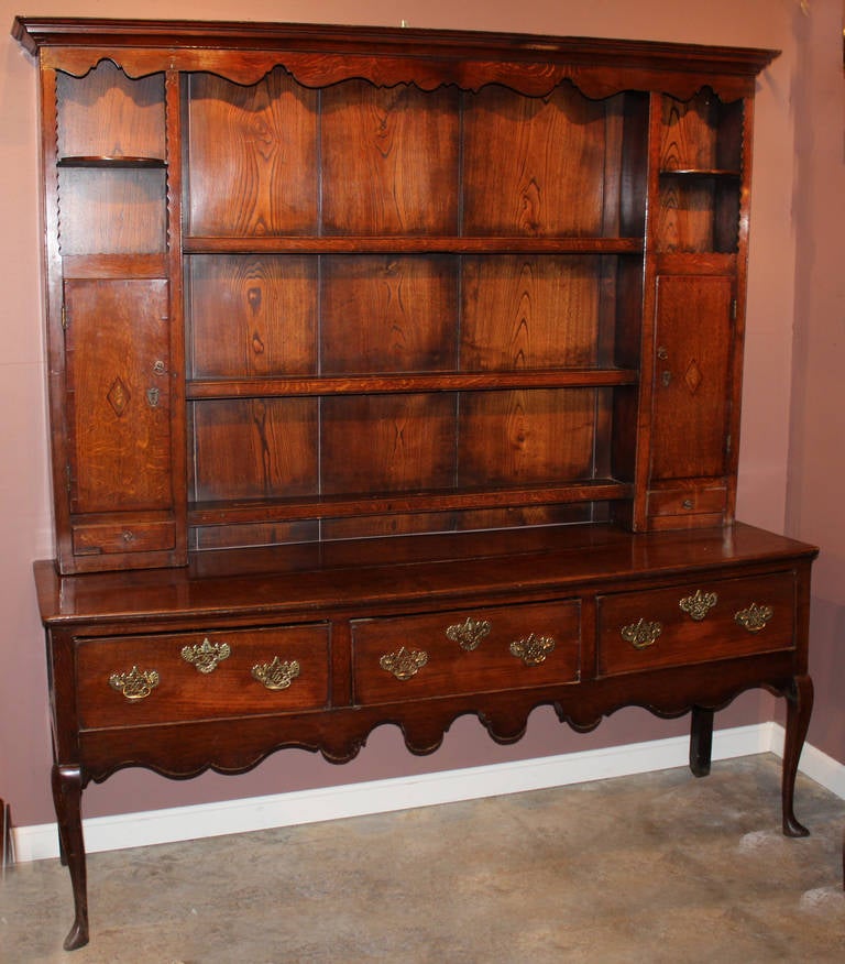 18th century English or Welsh oak three drawer dresser, original brasses, three shelf top is later, probably first quarter 19th century. Top has two side doors with small diamond shaped inlay decoration, revealing two shelves, over a single drawer