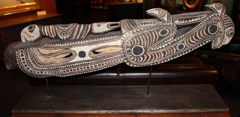 This  wooden carving with pigment decoration is a quality example of the type carved from a used canoe in the style of Papua New Guinea . The prow is in the form of a stylized crocodile head with birds sitting atop. The base is custom made.