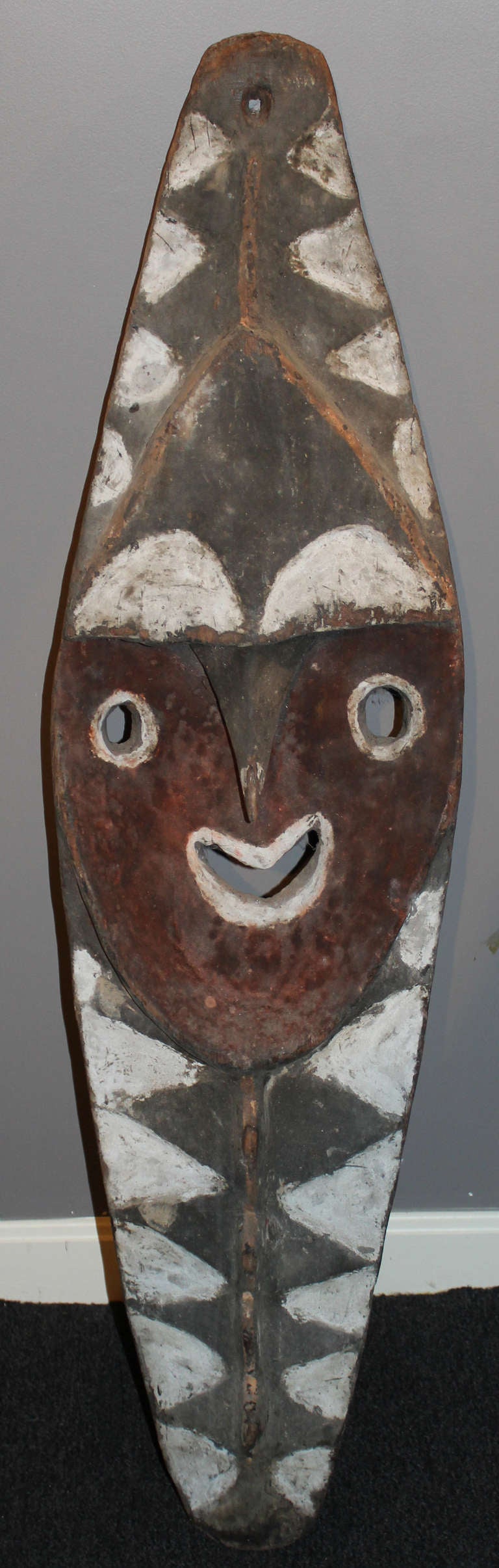 From Amaki village, the board of classical design is from Amaki village with a large central face deeply concave against the body, the nose pointing downward with smiling mouth. The upper and lower sections with alternating black and white
