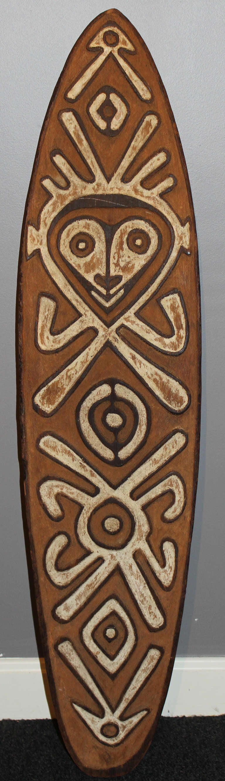 This board is Central Papuan Gulf style with white designs against a red ground with black outlining.