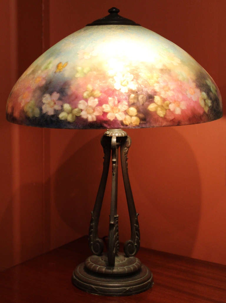 This wonderful floral table lamp has a reverse painted shade floral clusters of flowers in pink, yellow, and blue with frosted ice finish on the outside. The inside of the shade has several gold and orange enameled accent butterflies and the 3