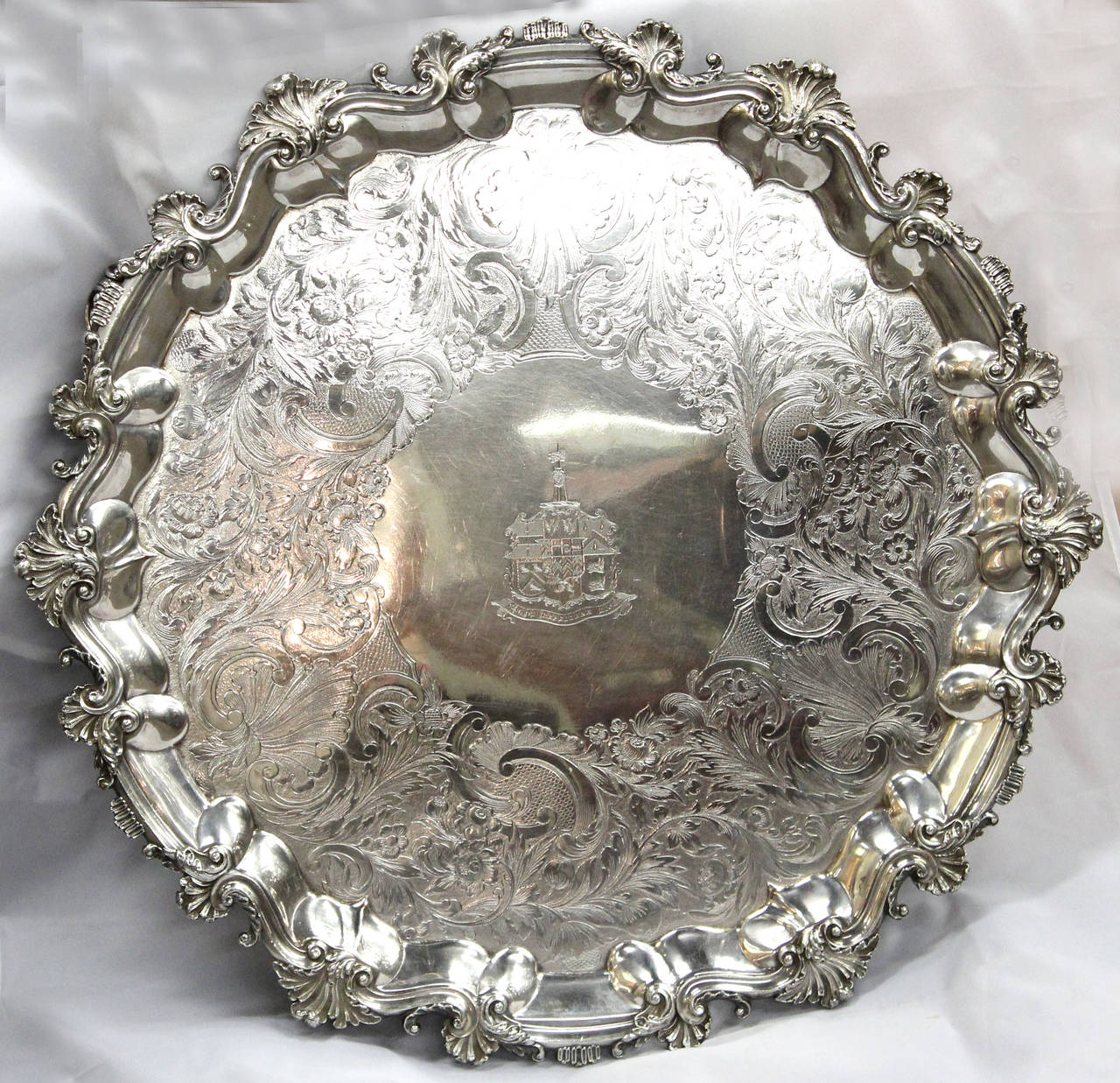 A large 19th century English Sheffield silver four-footed salver or tray, with beautiful chased scroll and floral decoration, including a family crest in the center with Latin motto “Vim Vi Repellere Licet,” translating to “We may repel force with