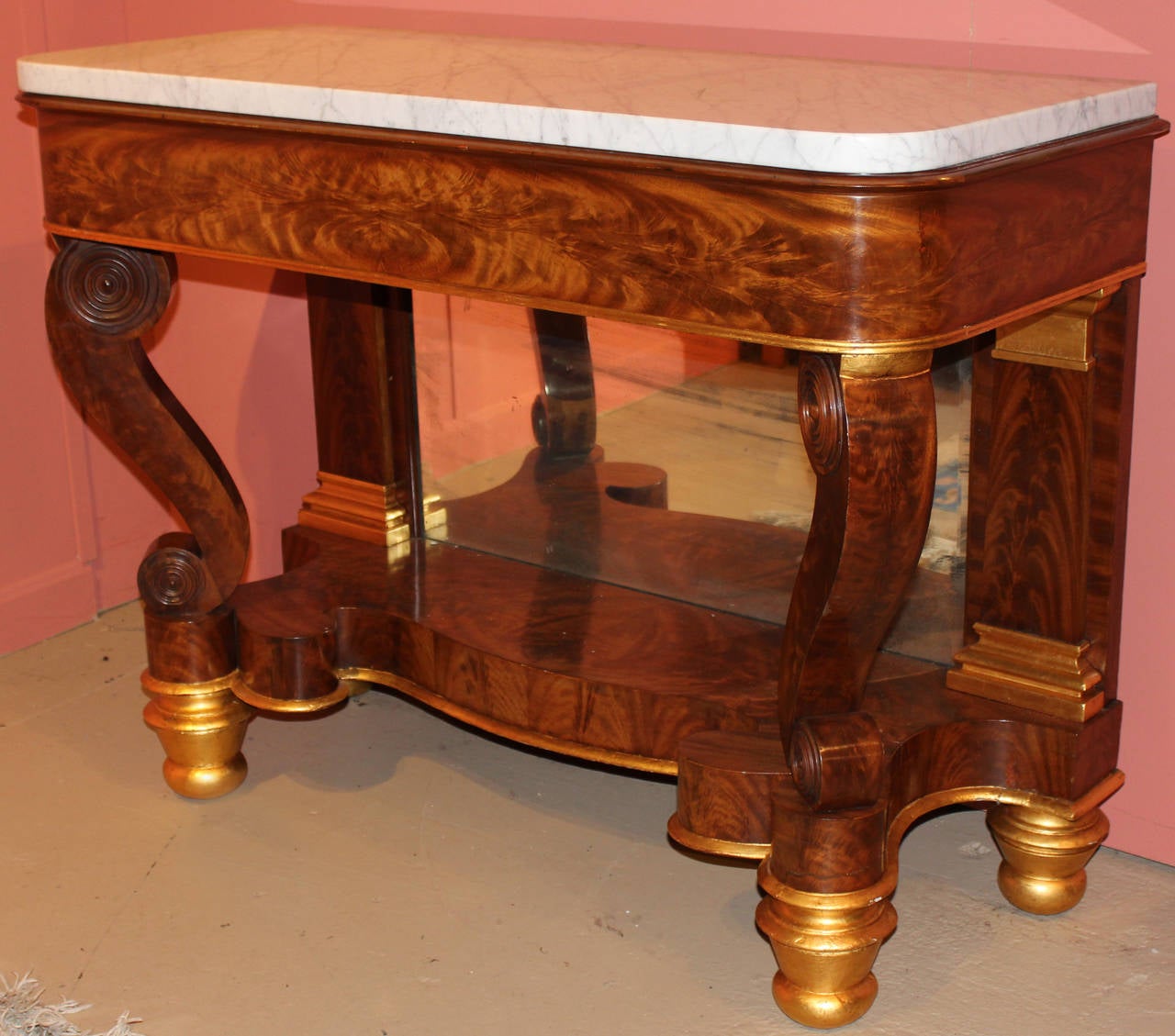 A nice example of a classical Empire pier or console table, Philadelphia circa 1825. The marble top supported by a frieze with book matched mahogany veneers above scrolled front legs and shaped apron with mirrored black plate flanked by tapered