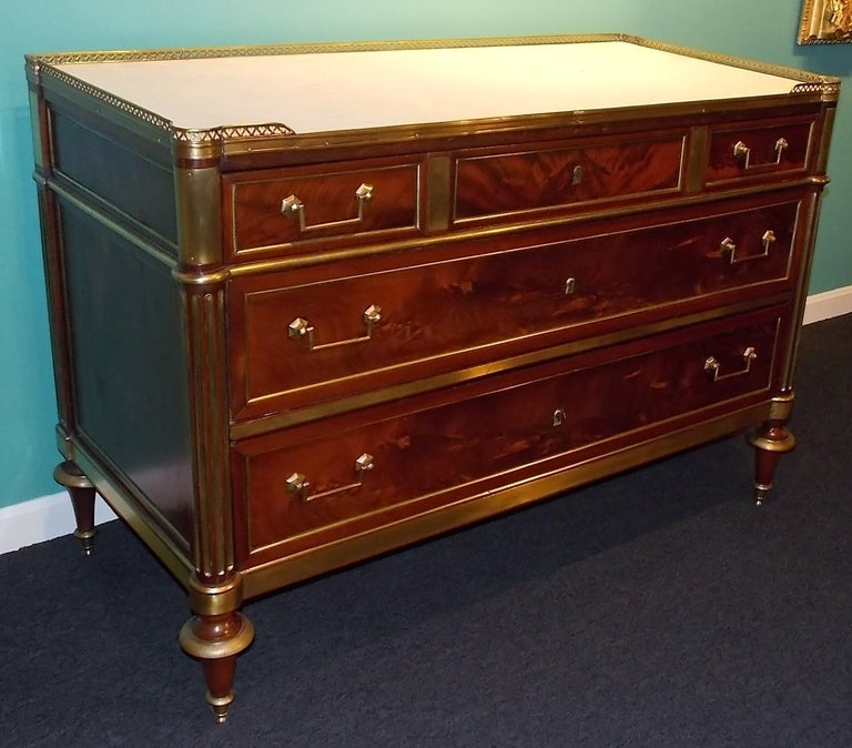 An exquisite three-drawer Louis XVI commode with brass mounts. The white marble top with brass gallery. Beautifully figured mahogany and in an excellent state of preservation.