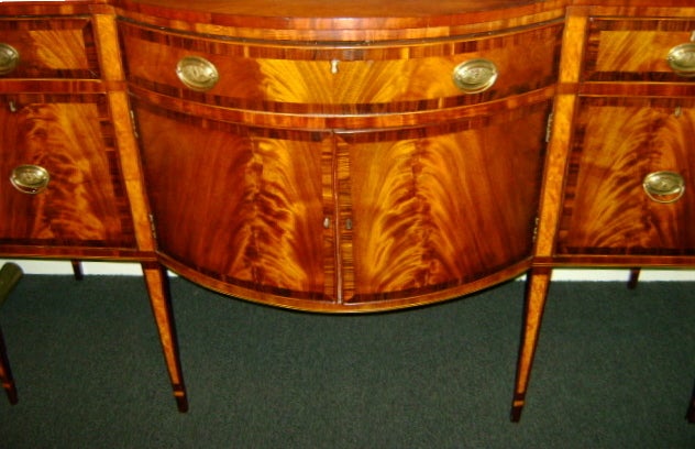 Elegant mahogany sideboard with shaped top and conforming case. Central drawer opens over two cabinet drawers flanked by additional drawers. All raised on tapered legs. Attributed to Goddard and Engs, Newport furniture makers.

Closely related