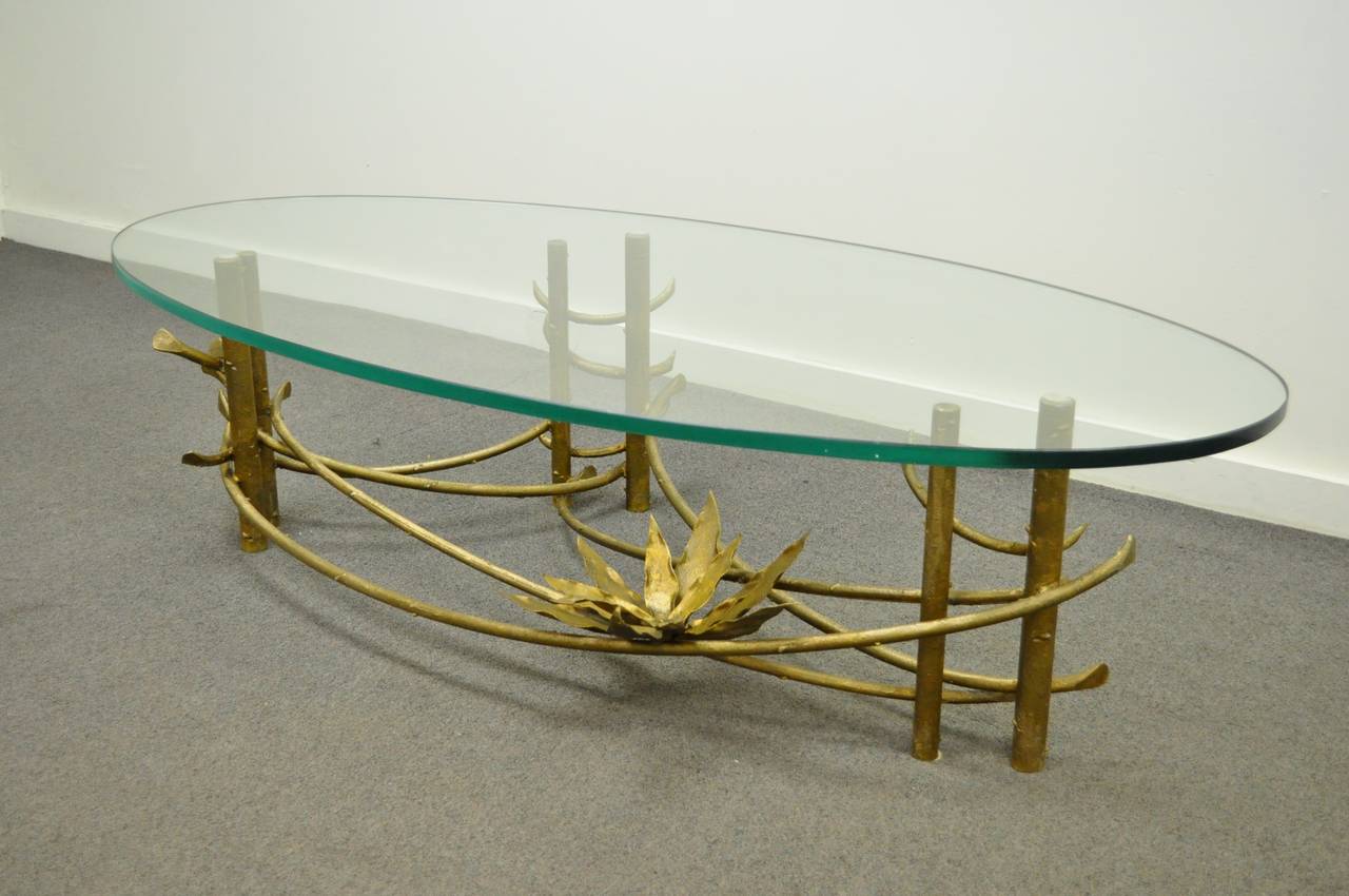 Remarkable hand-wrought and gilded vintage lotus coffee table attributed to Silas Seandel. This beautiful Hollywood Regency or Mid-Century Modern table features a gold gilt burnished finish, faux bois style detailing to the base, and a lotus blossom