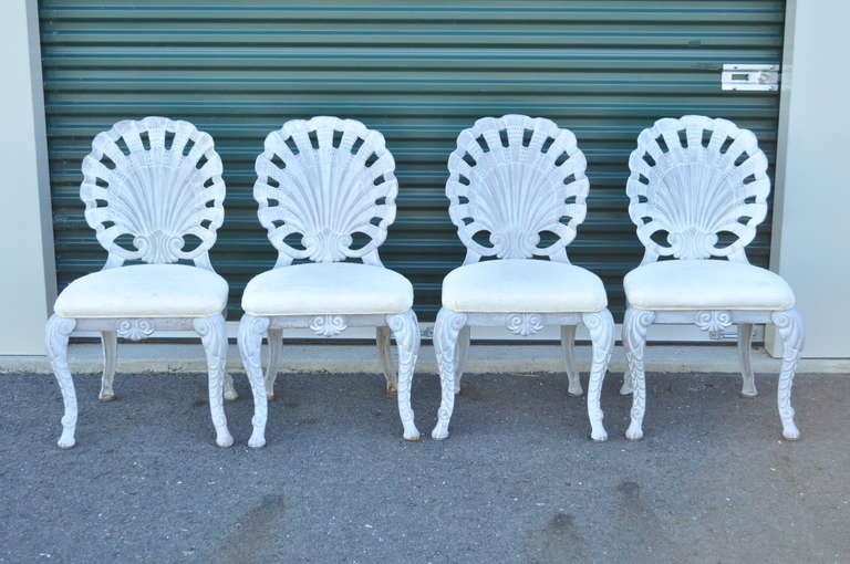 4 Vintage High Quality Cast Iron Grotto Style Patio Dining Chairs with a Lovely Shabby Chic White Washed Finish. The chairs feature a lovely sea shell motif with a large cutout shell design for the back with high quality construction. Each chair has