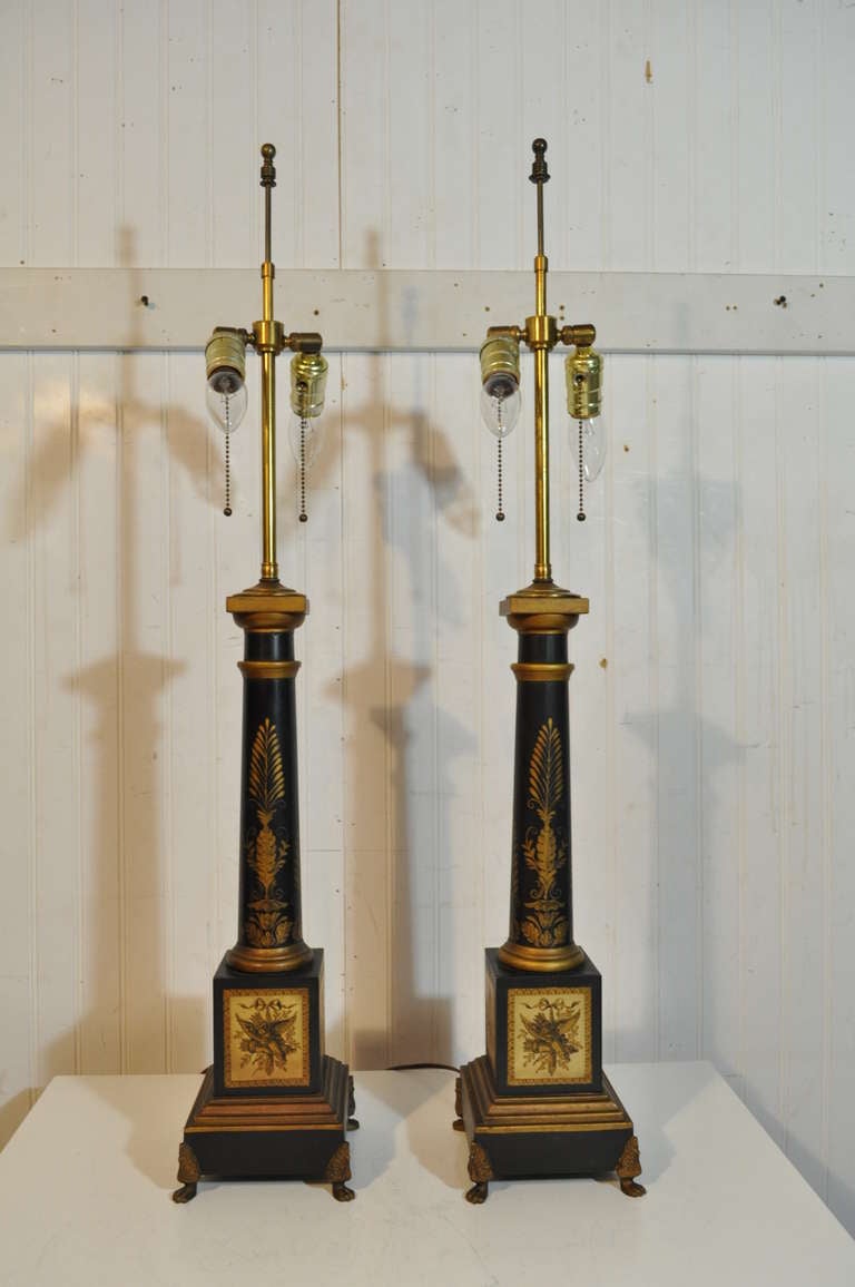Paire de lampes de table vintage françaises en forme de colonne en tole noir et or. Les lampes présentent un motif feuillagé sur le fût de la colonne:: et des motifs de torches et de carquois ailés alternant sur les côtés de la base.  Les douilles