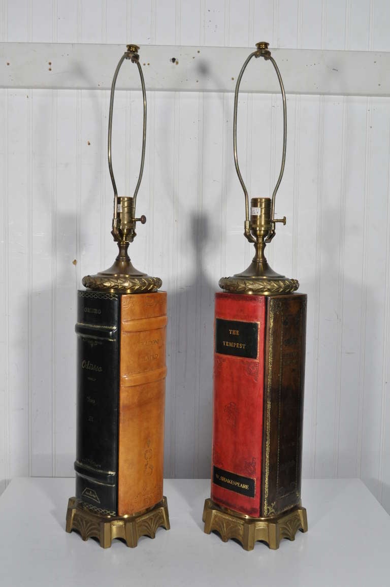 Remarkable quality pair of vintage brass and tooled leather bound book form table lamps. Each lamp features decorative brass foliate detailing with real leather book form bodies. 4 different color leather book forms feature some of the most classic