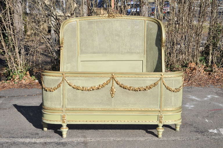 Fantastic, Circa 1900, French Painted Bed in the Louis XV / XVI Style with a Green and Gold painted finish, carved draped floral accents, caned head and foot board, and classic French Form. Many beds from this era were typically custom made so this