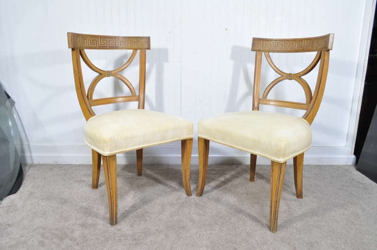 Set of 4 High Style Vintage Hollywood Regency Dining Chairs. The set features Greek key carvings on the top rail with saber front legs and nicely shaped back splats. Chairs have an attractive white-washed/lightly distressed finish for added