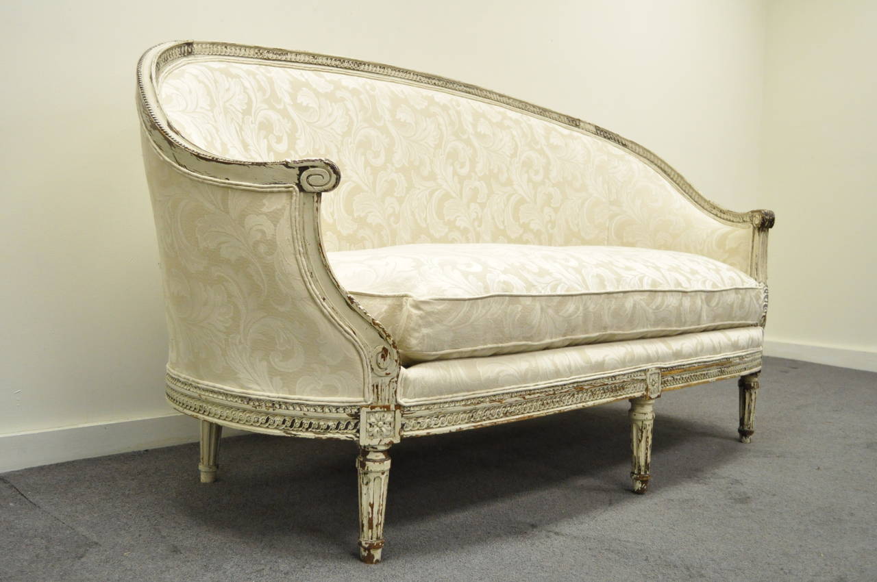 Remarkable antique French canape in the Louis XVI taste circa 1920. This stunning item features a intricately hand carved frame, carved reeded legs, ovoid shape, and desirable authentic distress / weathered finish to the frame from use over the