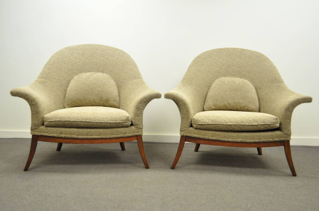 Stately pair of Vintage, Mid Century Modern, Wide, Sculpted Frame Lounge Chairs in the manner of Edward Wormley for Dunbar. This remarkable pair of vintage chairs features angled and tapered solid walnut legs, flared arms, rounded backs, and