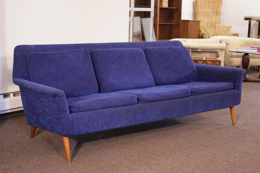 Blue upholstered sofa in the manner of Herman Miller. Item features Curved Arms, Blonde Wood Tapered Legs, Uniquely Reclined Frame.
