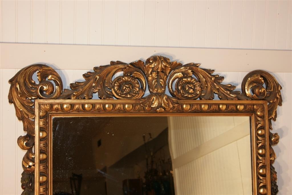 Antiker geschnitzter Rokoko/Barock-Spiegel mit einem sehr dekorativen, fein geschnitzten Rahmen aus vergoldetem Holz und polychromen, handgemalten und geschnitzten, mehrfarbigen Fruchtakzenten. Dieser atemberaubende Spiegel stammt etwa aus den