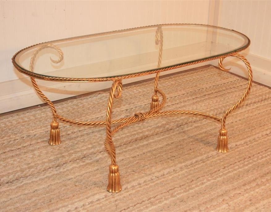 Beautiful Vintage Italian Tole Glass Top Oval Coffee Table. This unique table has very nice tassel form feet and rope turned legs. The frame is made of gilt metal. The form of this table is very chic and the size makes it easy to use in any homes