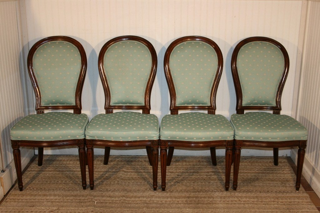 6 Henredon Solid Mahogany Regency Style Dining Room Chairs from the late 20th Century. This set includes 4 side chairs and 2 Arm chairs. This stunning set of chairs features, upholstered balloon backs, reeded tapered legs, carved knees, and the most