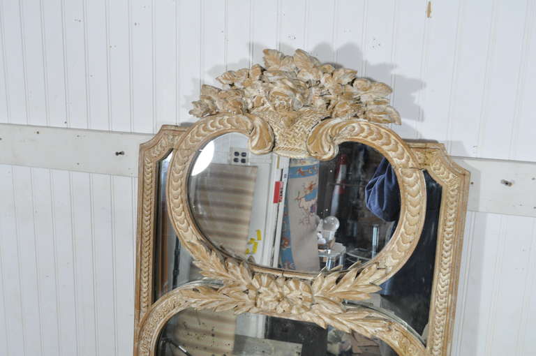 Vintage French Louis XV Style hand carved, distress painted, whitewash finished, trumeau mirror. The frame of the piece is carved with a lovely bouquet at the top. While the upper sections of the mirror have clear glass, the lower portion of the
