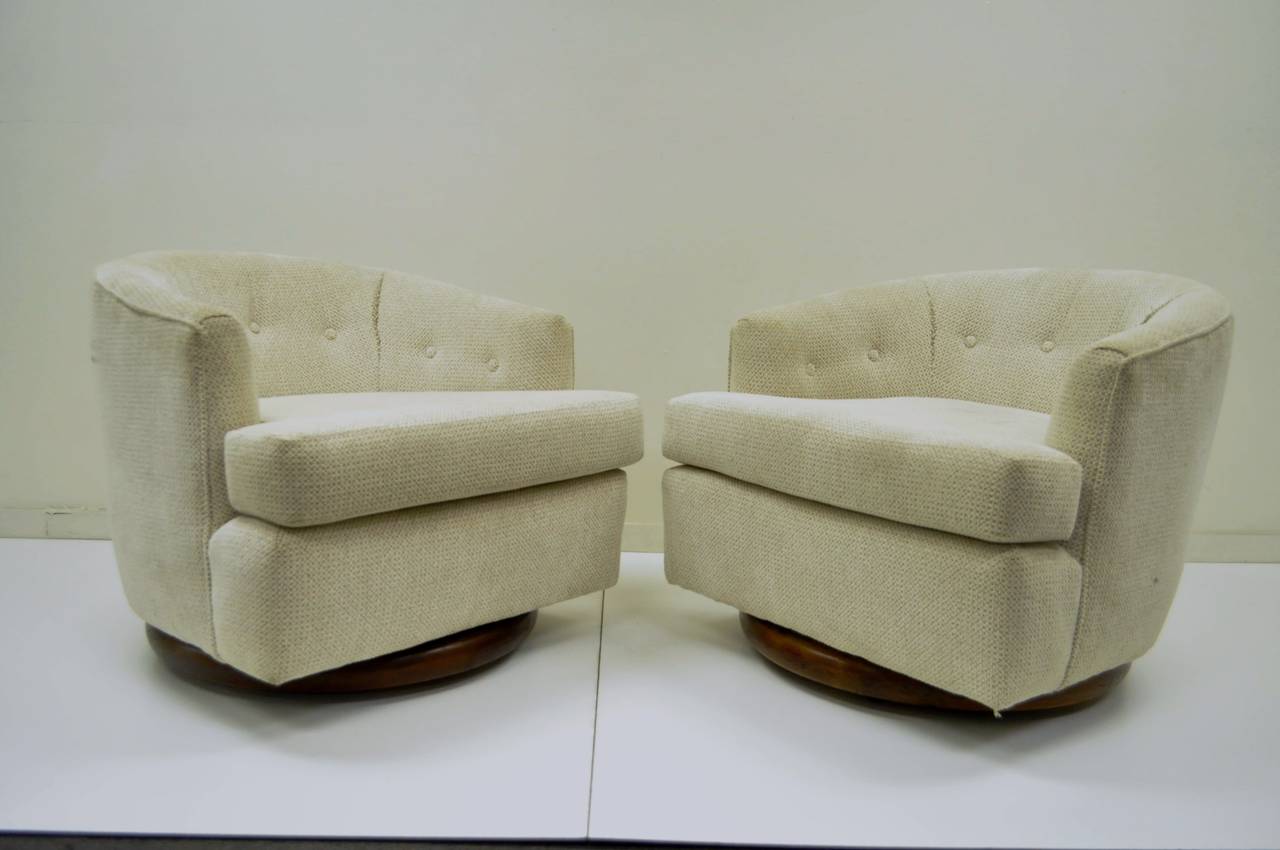 Very unique pair of vintage, mid century modern, barrel back club chairs with revolving solid walnut sculpted edge plinths on rolling casters after Milo Baughman. The pair features clean modern lines, sculpted wood plinths, and remarkable form. The